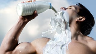 Muskulöser Mann leert sich lustvoll Milch ins Gesicht