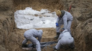 Menschen in Schutzanzügen exhumieren Leichen in Butscha