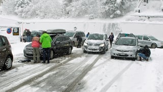 Auf der Hauptstrasse von Göschenen nach Andermatt herrscht derzeit Schneekettenpflicht. Deshalb werden auf dem Parkplatz die Ketten montiert. (Keystone) 