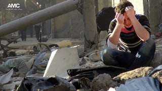 Ein verzweifelter Mann sitzt auf Trümmern eines Hauses in Aleppo.