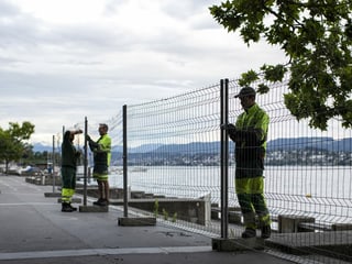 Mitarbeiter der Stadt entfernen die Absperrgitter rund um das Zürcher Seebecken. 