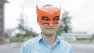 Ein Mann mit einer orangen Maske über den Augen. 