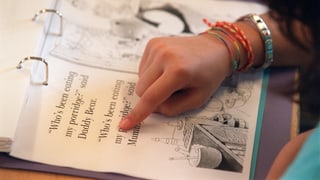 Schülerin zeigt mit Finger auf eine englische Textpassage in ihrem Lernordner