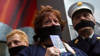 Menschen protestieren mit verbundenem Mund.