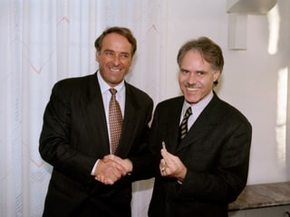 Bundesräte Adolf Ogi und Moritz Leuenberger schütteln Hände.