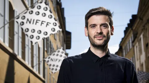 Portrait eines Mannes mit einer Flagge im Hintergrund mit der Aufschrift NIFFF.