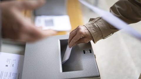 Jemand legt seinen Wahlzettel in die Urne.