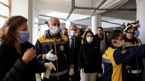 Menschen in Schutzkleidung und Masken in einem Gebäude.