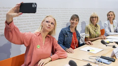 Lilian Studer macht ein Selfie von sich und anderen Frauen an einem Rednerpult im Medienzentrum Bundeshaus