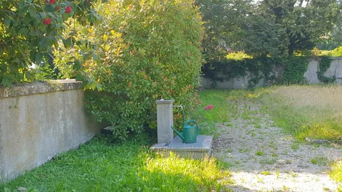 Mauer um eine Wiese, ein Brunnen.