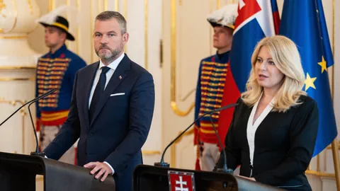 Politiker bei einer Pressekonferenz mit Wachen im Hintergrund.