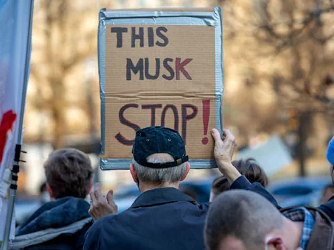 Person hält Protestplakat mit Aufschrift.