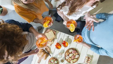 Auf dem Bild sind vier Menschen mit einem Glas in der Hand zu sehen.