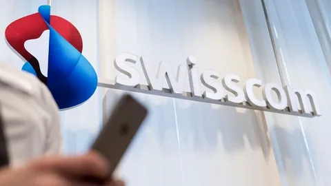 Swisscom-Logo. Im Vordergrund eine Person mit einem Handy.