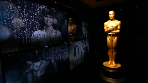 Grosse Oscar-Statue in Los Angeles vor einer Leinwand mit Bildern von früheren Oscar-Verleihungen.