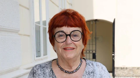 Frau mit kurzen roten Haaren und runder Brille.