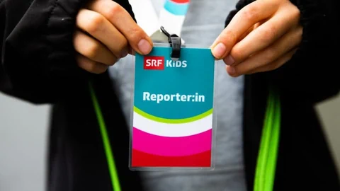 Kind hält Reporter:innen-Badge