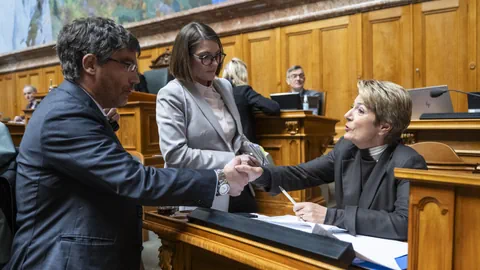 Personen schütteln sich die Hand in einem Sitzungssaal.