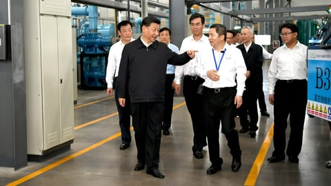 Chinas Machthaber Xi Jinping in einer Fabrikhalle mit Begleitern.