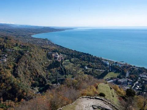 Luftaufnahme der abchasischen Küstenlandschaft mit Wäldern und Meerblick.