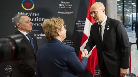 Drei Menschen schütteln Hände bei der Ukraine Mine Action Conference.