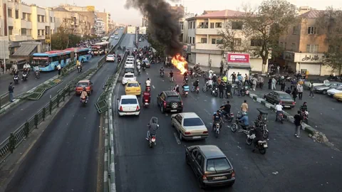 Protestierende auf einer Strasse, ein Feuer brennt.