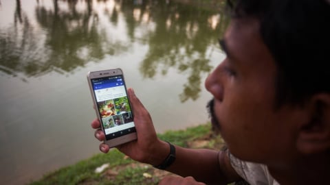 Ein Mann aus der ethnischen Minderheit der Rohingya schaut auf Facebook auf sein Mobiltelefon