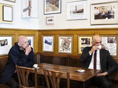 Daniel Koch und Alain Berset sitzt an einem Tisch. Berset trinkt einen Kaffee.