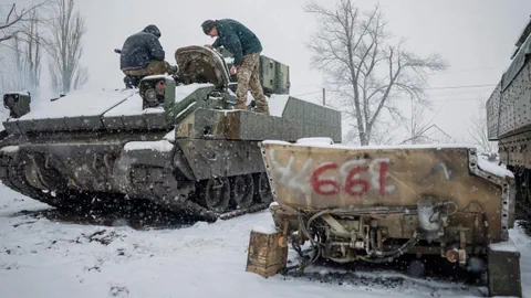 Soldaten reparieren Panzer im verschneiten Gebiet.