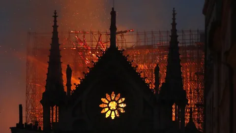 Hinter einer Kirchenfassade brennt es in der Dunkelheit.