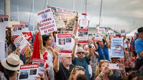 Protestierende mit Schildern an Lazzarinis Festansprache in Lausanne.