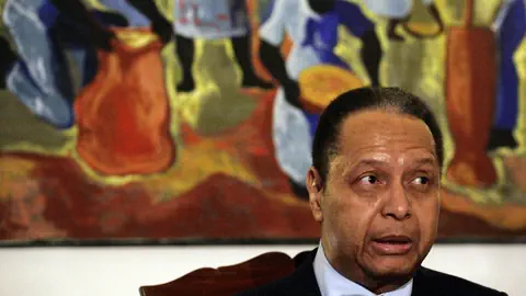 Jean-Claude Duvalier vor einem farbenfrohen Gemälde.