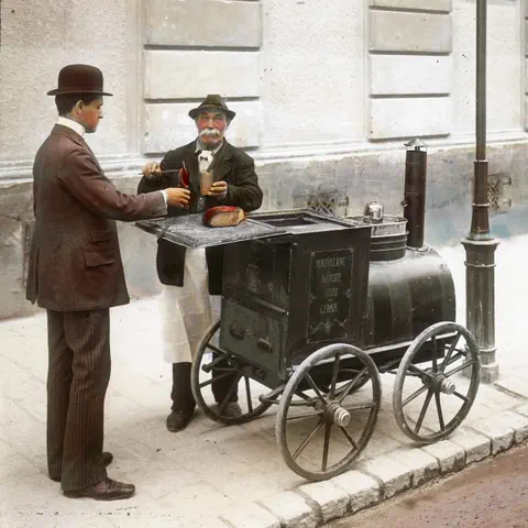 Mann kauft Essen von Strassenverkäufer mit Wagen.