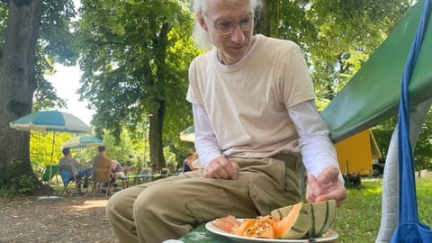 Ein Mann sitzt auf einer Bank und ködert eine Wespe.