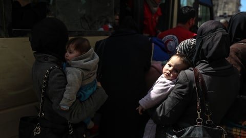 Frauen mit Kindern steigen in ein Bus ein.