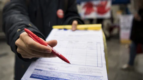 Person bietet einen roten Stift und ein Formular an.