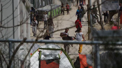 Menschen im Lager Moria gehen einen Weg entlang, darunter auch Kinder..