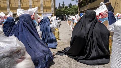 Frauen in Ganzkörperverhüllung sitzen am Boden.