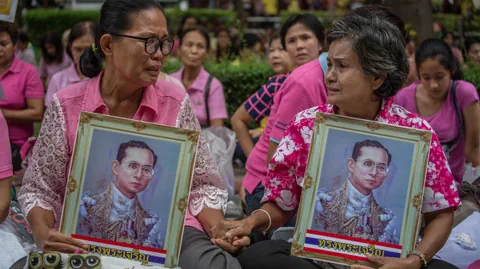 Thailänderinnen tragen gerahmte Bilder des Königs.