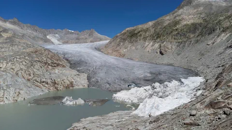 Gletscher mit Eis und Schmelzwassersee in bergiger Landschaft.