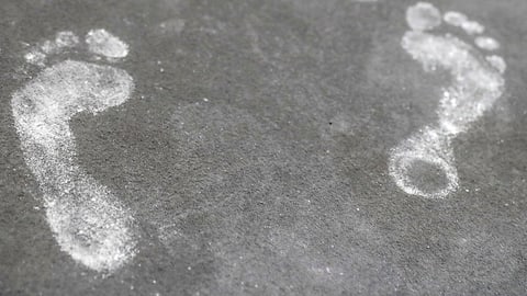 Zwei weisse Fussabdrücke auf Asphalt