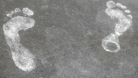 Zwei weisse Fussabdrücke auf Asphalt