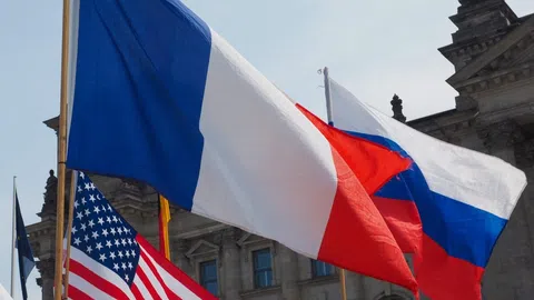 Die französische, US-amerikanische und russische Flagge wehen im Wind.