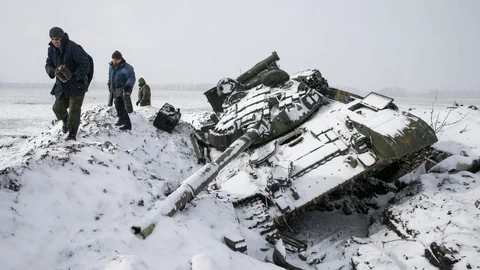 Zerstörter Panzer, Menschen in schneebedecktem Feld.