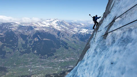 Mann klettert an Felswand mit Eis.