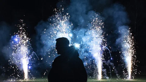 Ein Mensch steht vor mehreren Feuerwerk-Pyramiden.