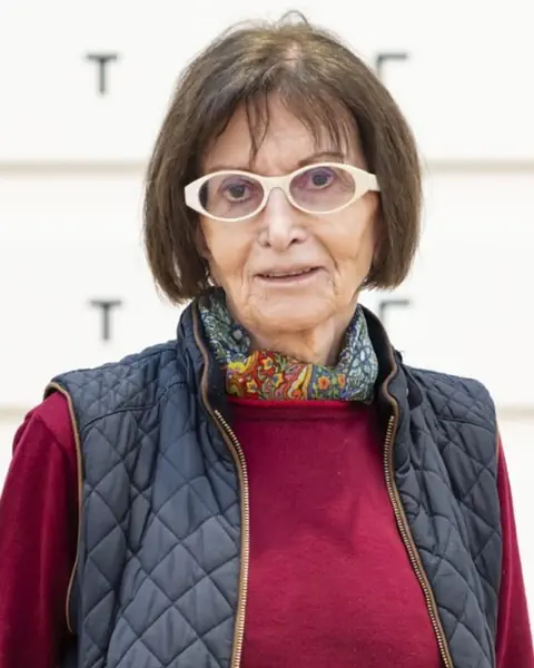 Portrait von alter Frau mit braunen Haaren und weisser runder Brille in rotem Pullover