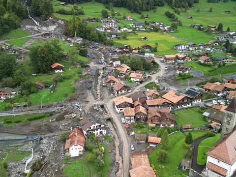 Luftaufnahme eines Dorfes mit Erdrutsch und beschädigten Häusern.