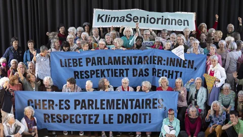 Gruppe von Seniorinnen hält Banner mit Klimabotschaften.