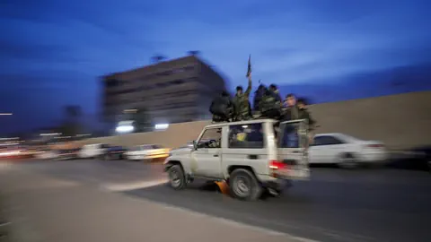 Unscharfes Bild von Personen auf einem fahrenden Geländewagen bei Nacht.